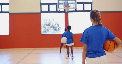 Girls Practicing Basketball in School Gym