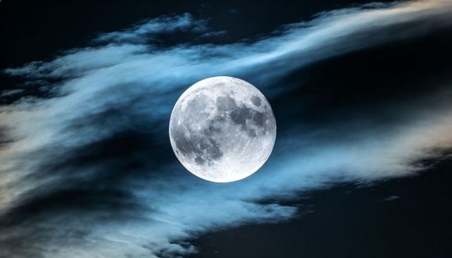 Glowing Full Moon with Wispy Clouds Revealing Cratered Surface and Halo Over Dark Night Sky