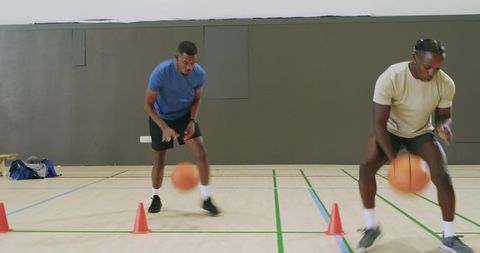 Group of african american men dribbling through cones during basketball agility training