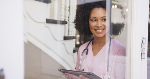 Happy Nurse with Tablet Looking Out Window in Modern Hospital