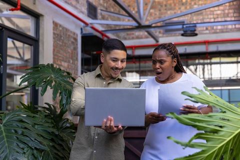 Coworkers Collaborating with Laptop in Modern Urban Office