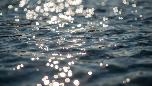 Shimmering sunlit ocean surface with teal ripples and bokeh sparkle