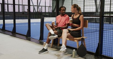Diverse Athletes Enjoying Coffee Break on Padel Court Bench