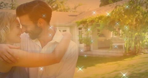 Romantic couple embracing on sunlit backyard lawn with porch golden hour glow and sparkles