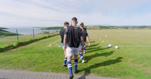 Male Soccer Team Preparing for Drill on Coastal Field