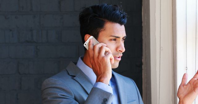 Businessman talking on smartphone while looking outside window - Download Free Stock Images Pikwizard.com