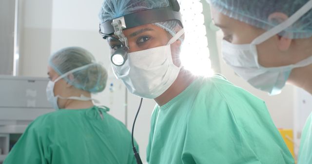 Medical team performing surgery in operating room, surgeons wearing green scrubs and surgical caps, looking focused. Ideal for use in healthcare presentations, medical brochures, educational materials, and websites highlighting surgical procedures and hospital environments.