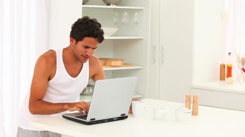 Casual Man Working on Laptop in Bright Home Kitchen