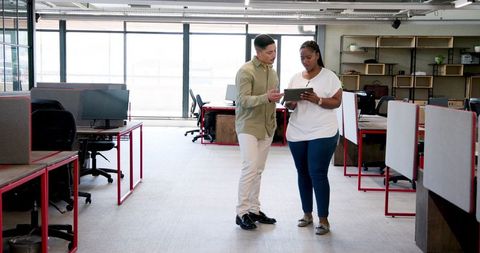 Colleagues Collaborating with Tablet in Modern Open-Plan Office