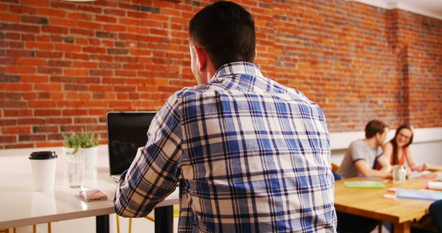 Man Working on Laptop in Modern Office with Colleagues - Download Free Stock Images Pikwizard.com