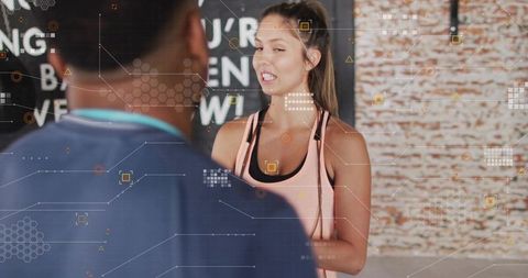 Female trainer demonstrating exercise to client in urban gym with industrial brick wall
