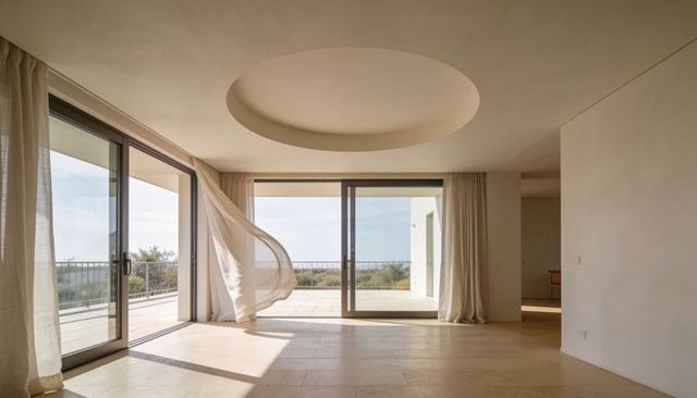 Sunlight streaming through floor-to-ceiling sliding glass doors with sheer curtains