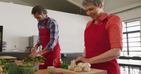 Smiling Seniors Preparing Fresh Vegetables in Kitchen