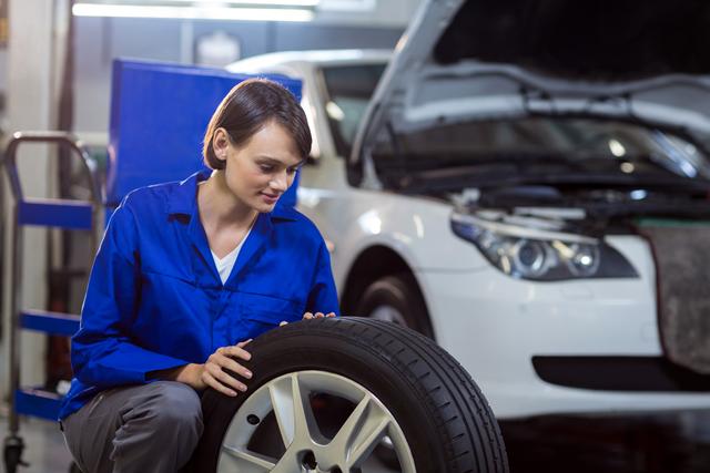 Female mechanic checking a tyre in repair garage
