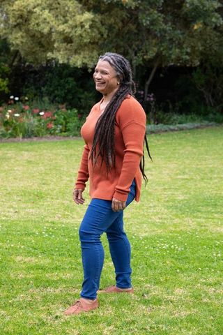 Joyful woman strolling in park amidst lush greenery and flowers