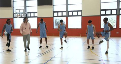 Dedicated coach leading athletic team in dynamic warm-up drill