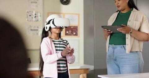 Young student using VR headset in classroom while African American teacher guiding lesson