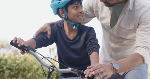 Father Teaching Son Bicycle Riding Outdoors with Helmet Safety
