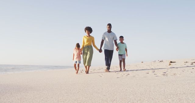 Smiling african american holding hands and walking on sunny beach. healthy, active family beach holiday.