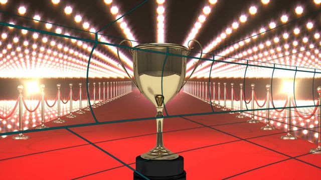 Golden trophy placed on red carpet adorned with spotlights. Ideal for representing victory, accolades, achievements, and special ceremonial events. Perfect for use in articles, advertisements, event invitations, and motivational materials emphasizing success and recognition.