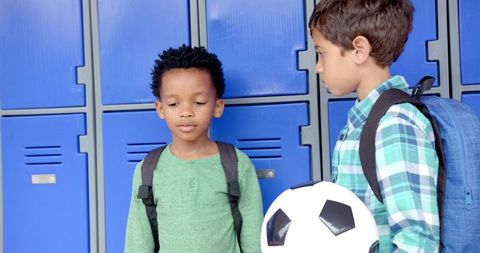 Two Boys Holding Soccer Ball Near School Lockers