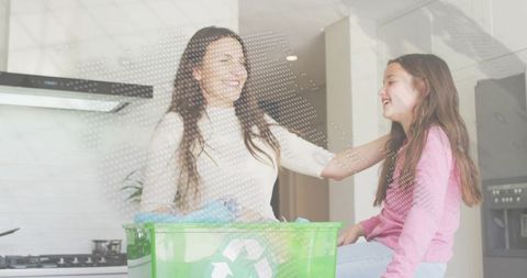 Laughing mother and daughter sharing moment in kitchen while recycling