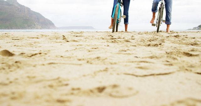 Two Cyclists on Beach with Mountain View - Download Free Stock Images Pikwizard.com