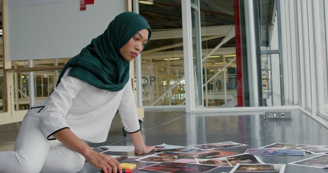 Muslim Woman Curating Photographs in Modern Office - Download Free Stock Images Pikwizard.com