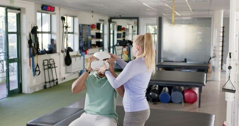 Assisting Male Patient with VR Headset in Rehabilitation Center