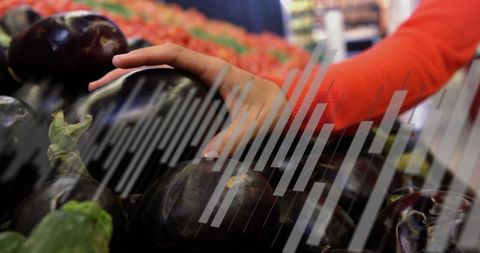 Woman selecting eggplants in grocery store aisle with vibrant vegetables