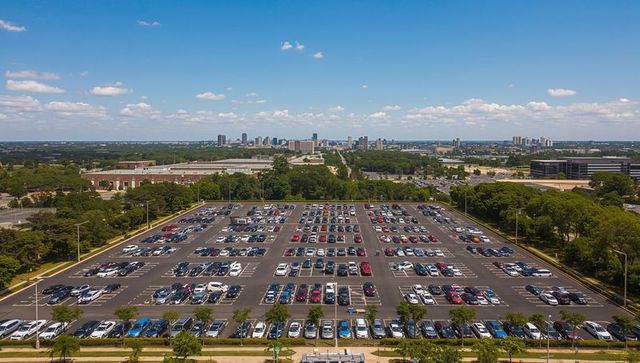 Displaying expansive suburban campus parking lot aerial perspective with distant skyline