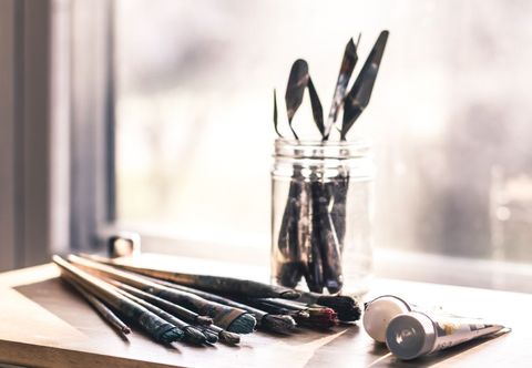 Artistic tools on wooden surface with sunny backdrop