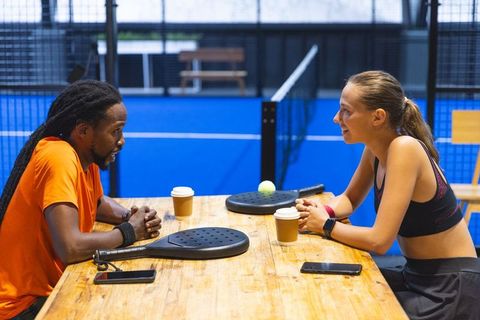 Diverse Friends Sharing Coffee and Conversation in Padel Court Lounge