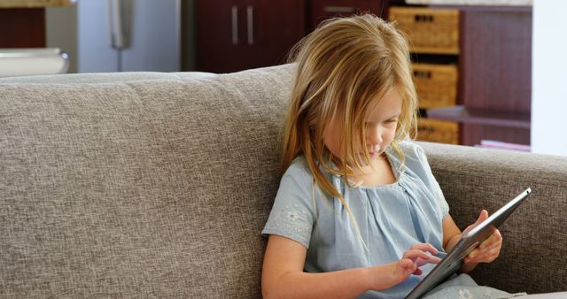 Young girl playing with tablet on couch - Download Free Stock Images Pikwizard.com