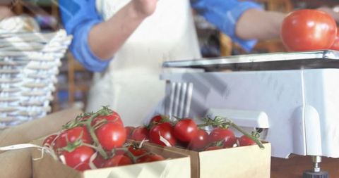 Vendor weighing fresh vine tomatoes on vintage scale at rustic market stall