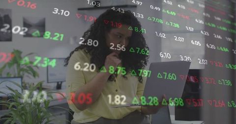 Woman analyzing stock market data on laptop in office