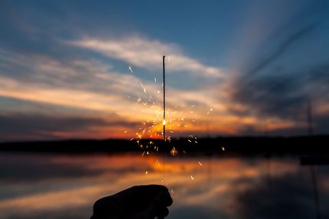Sparkler Glowing Against Beautiful Sunset Over Water