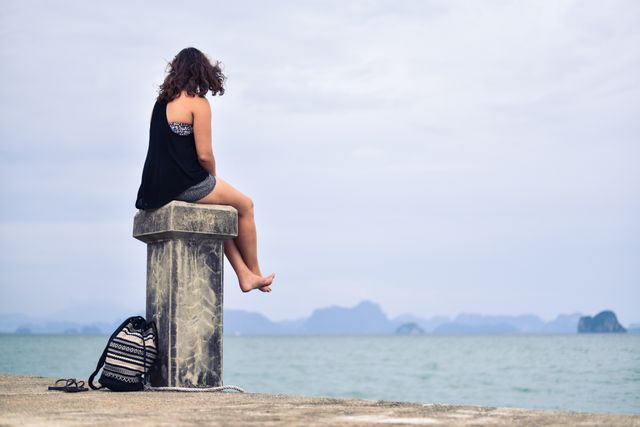 Woman Sitting on Seaside Cliff Watching Calm Ocean Horizon - Download Free Stock Photos Pikwizard.com