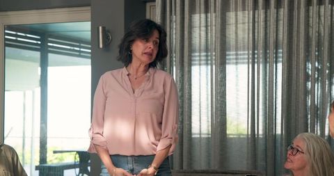 Mid-adult woman speaking in group meeting at modern home