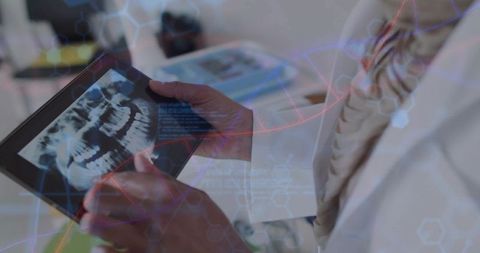 Dental professional reviewing digital panoramic jaw x-ray on tablet with dna data overlay