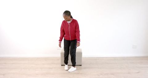 Confident Woman in Red Jacket Walking in Minimalist Room