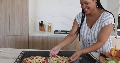 Young woman baking pizza in modern kitchen with joyful expression