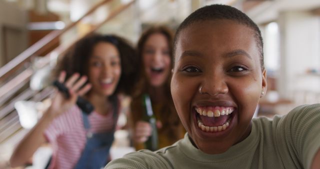 Three women are happily taking a selfie indoors. The image showcases diverse friends excitedly celebrating and laughing. Suitable for promoting joyful gatherings, social engagements, friendship, and celebratory events.