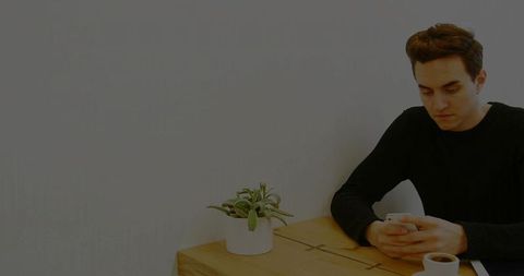 Man using smartphone in chic minimalist cafe corner