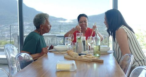 Multigenerational african american women sharing meal and serving bread on sunlit balcony