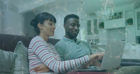 Couple collaborating on laptop at home with digital network overlay for remote teamwork
