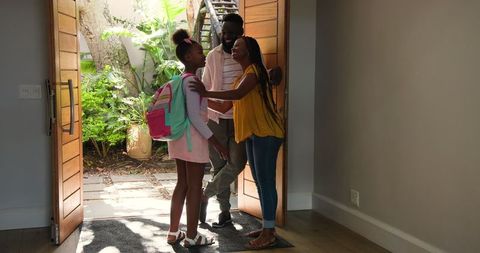 Family bonding at home, mother adjusting daughter's hair