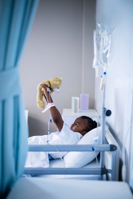 Patient playing with teddy while resting on the bed at hospital