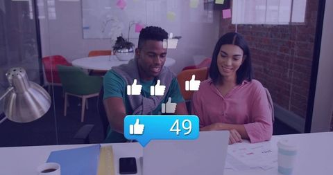 Collaborating over laptop in modern office with social likes overlay and teamwork boost