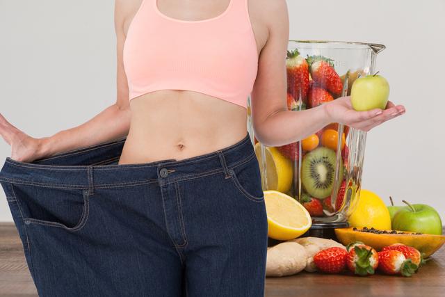 Digital composite of Midsection of woman in loose jeans holding apple